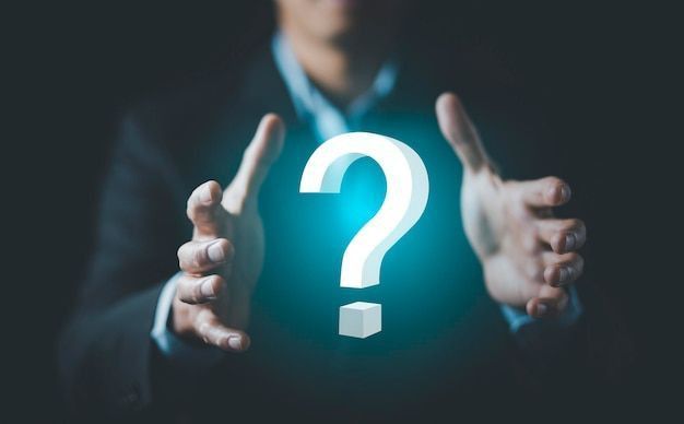 generate alt text this picture A person in a suit is holding their hands up, palms facing inwards, as if presenting or cradling something. Between their hands, a large, glowing white 3D question mark hovers, surrounded by a subtle blue aura. The background is dark and blurred, drawing focus to the hands and the prominent question mark, symbolizing inquiry, uncertainty, or the search for answers